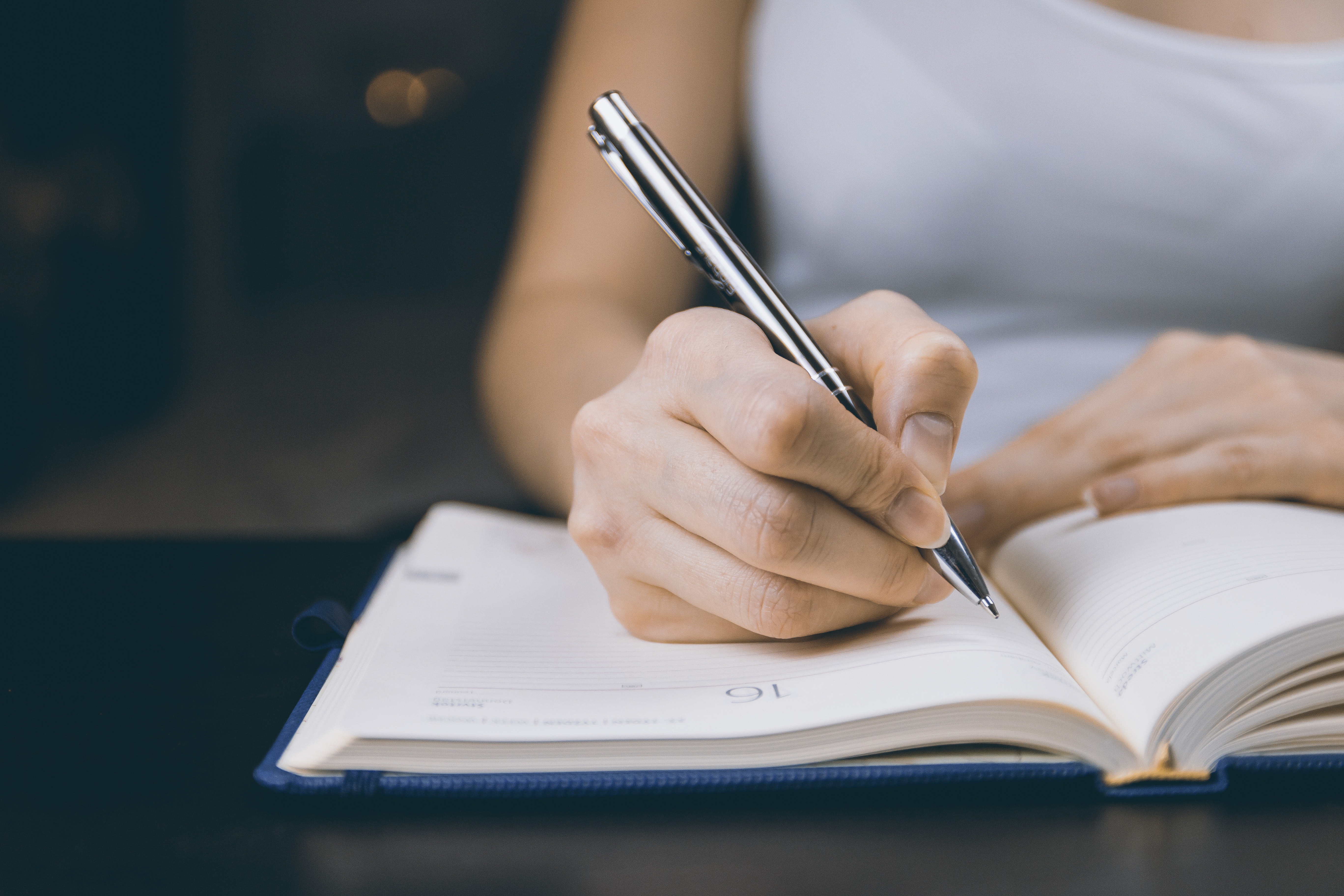 A woman writing in a pad at a desk